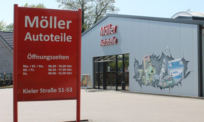 Asicht des Ladens von Möller Autoteile von außen mit einem Öffnungszeitenschild im Vordergrund